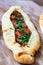 Closeup of an appetizing pide flatbread stuffed with roasted meat, tomato and greens topping