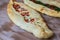 Closeup of an appetizing pide flatbread stuffed with tomato, greens and cheese topping