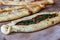 Closeup of appetizing pide flatbread variety stuffed with toppings on a wooden surface