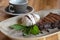 Closeup of appetizing slice of dark chocolate cake with ice cream and out of focus coffee cup in background