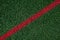 Closeup of artificial grass turf on a recreational sports field, with a red stripe, as a graphic background