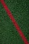 Closeup of artificial grass turf on a recreational sports field, with a red stripe, as a graphic background