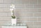 Closeup artificial plant with white orchid flower on pink flower pot on wood weave table on blurred brown brick wall texture