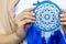 Closeup artistic woman posing holding dreamcatcher with bright blue feathers artwork