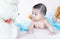 Closeup asian baby infant laying comfortably on bed playing with bear doll on softness cushion