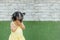 Closeup asian girl take her hands off the face and play hidden with someone on grass floor and brick wall textured background with
