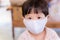 Closeup Asian little boy wear a mask made of white cloth to protect against an epidemic virus and toxic dust situation.