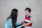 Closeup asian mother is comforting her crying son on marble stone wall textured background