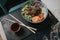 Closeup of Asian trendy food raw organic poke bowl and chopsticks on the table in a restaurant