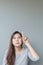 Closeup asian woman holds up one finger point to space with boring face emotion on blurred cement wall textured background with co