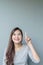 Closeup asian woman holds up one finger point to space with smile face on blurred cement wall textured background with copy space