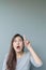 Closeup asian woman holds up one finger point to space with surprise face emotion on blurred cement wall textured background with