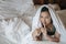 Closeup asian woman lie on bed under blanket and make a gesture to tell the sound softly