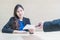 Closeup asian working woman receive work document from her boss with unwilling face in meeting room on blurred wooden desk and