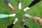 Closeup of athletes wearing sports shoes and standing in circle on green grass