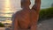 Closeup athletic man training at sea sunset. Muscular male back at ocean view.