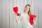 Closeup attractive blonde girl looks at camera showing many red heart shaped pillows