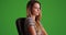 Closeup of attractive female millennial sitting on green screen