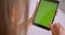 Closeup back portrait of young attractive caucasian woman using tablet with green chroma key screen in office indoors