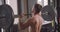 Closeup back view portrait of shirtless muscular caucasian man lifting weights in the gym indoors