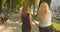 Closeup back view portrait of two female friends walking in park outdoors