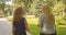 Closeup back view portrait of two pretty caucasian female friends walking in park outdoors