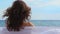 Closeup back view of tender feminine woman relaxing on beach at seaside, summer