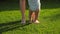 Closeup of barefoot baby boy and mother standing on fresh green grass at park. Concept of healthy lifestyle, child