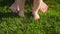 Closeup of barefoot baby standing on fresh green grass with mother. Concept of healthy lifestyle, child development and