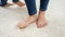 Closeup of barefoot mother waiting for her son running around her on white carpet