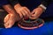 Closeup Barefoot Old Man Repairs Fishing Basket on Blue