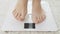 Closeup of barefoot woman using digital scales and checking her weight. Concept of dieting, loosing weight and healthy