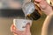 Closeup Barista in preparing proper cappuccino pouring milk froth in a cup