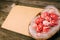 Closeup basket with Easter red eggs on vintage sheet of paper on the right side of wood table. Top view horizontal background