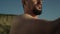 Closeup bearded karate man naked body warming up on seashore summer day.