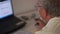 Closeup Bearded Old Man Sits in Front of Notebook at Table