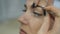 Closeup of beautician hands using tweezers on woman`s eyebrow at beauty salon