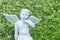 Closeup beautiful cement angle statue on blurred green plant textured background
