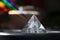 Closeup of a beautiful silver transparent pyramid with rainbow shines on a blurry background