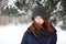 Closeup beautiful winter portrait of young adorable redhead woman in cute knitted hat winter snowy park