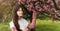 Closeup beautiful young brunette girl 11-12 years under the flowering pink tree