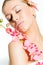 Closeup on beautiful young lady with perfect skin, closed eyes and luxury jewelry earring holding orchid flower