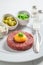 Closeup of beef tartare with chives, gherkin and yolk