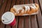 Closeup of beignet pastries, donuts in a paper takeaway box and a cup of coffee on a bench in park. The delicious deserts covered