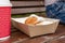 Closeup of beignet pastries, donuts in a paper takeaway box and a cup of coffee on a bench in park. The delicious deserts covered