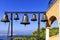 Closeup of bells against a blue sky, mediterranean pine and sea coast in blur, Greece, August 2019