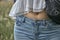 Closeup of the belly of a female wearing light blue jeans and a white shirt in a field