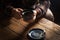 Closeup black americano coffee in blue cup in male hand, saucer with vintage tea spoon on background wooden brown vintage village