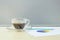 Closeup black coffee in transparent cup of coffee with work paper and pencil on blurred wooden desk and frosted glass wall texture