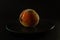 Closeup of a black plate of a peach on dark background